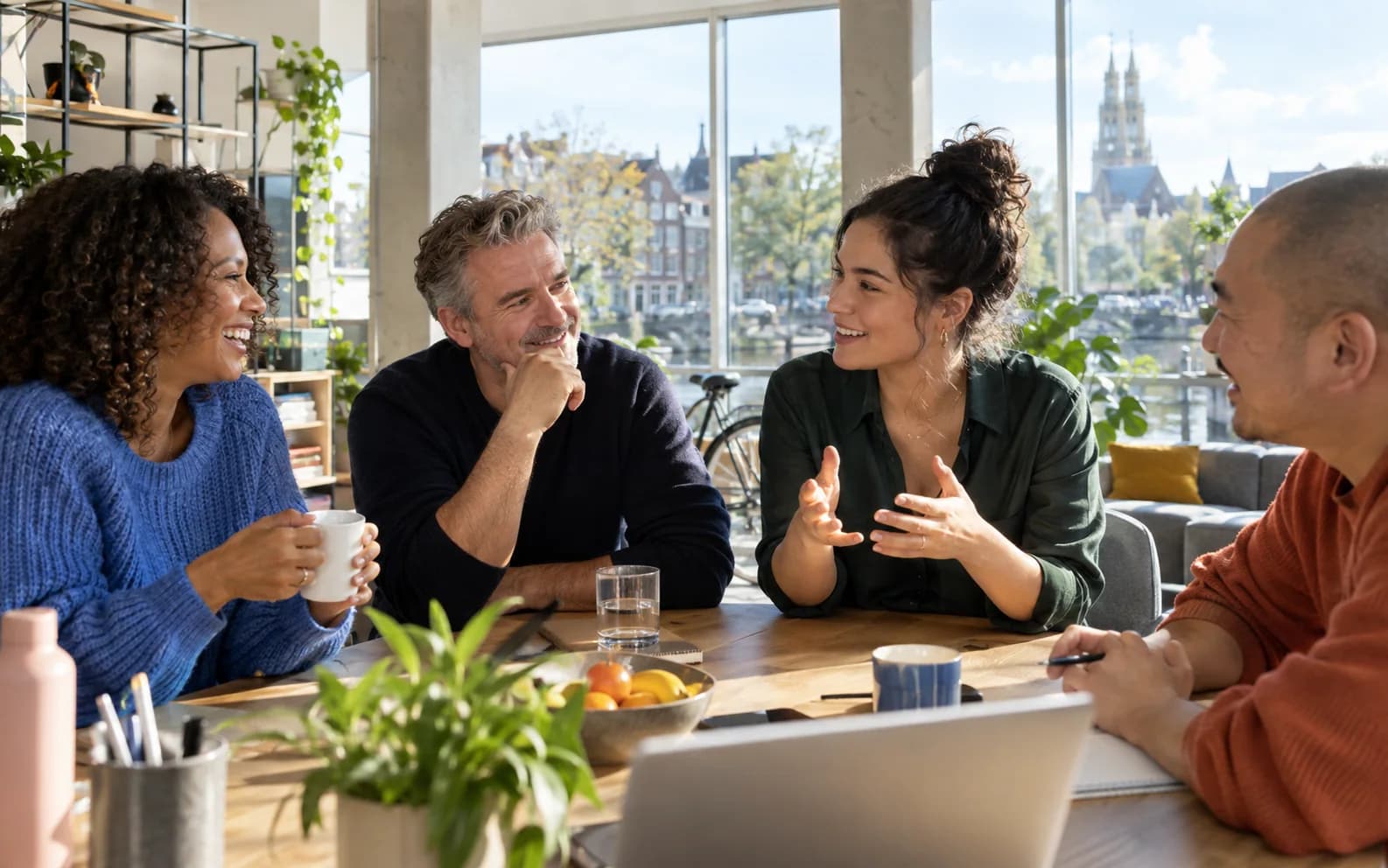 Four professionals talking in a sunlit Dutch workspace